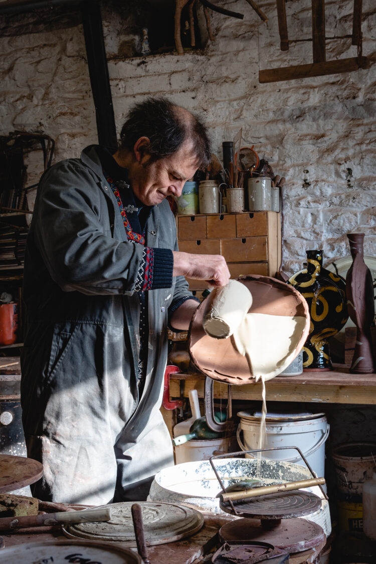 Potter Dylan Bowen decorates a slipware plate