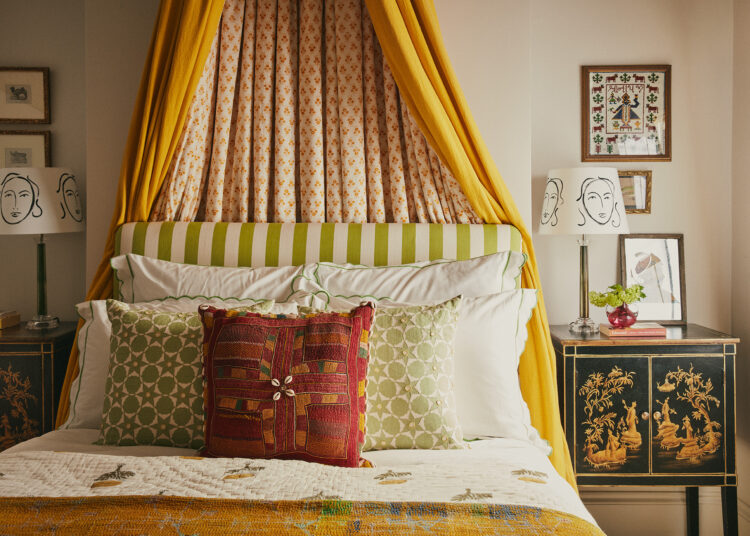 Bed with colourful cushions and yellow canopy