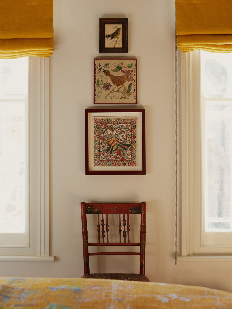 Framed Indian fabrics set between two windows with yellow blinds