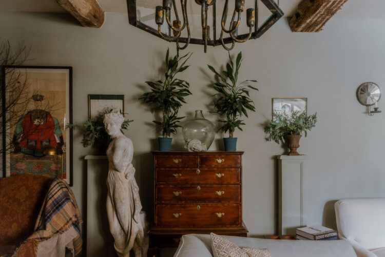 Green wall with antique chest of drawers and statue