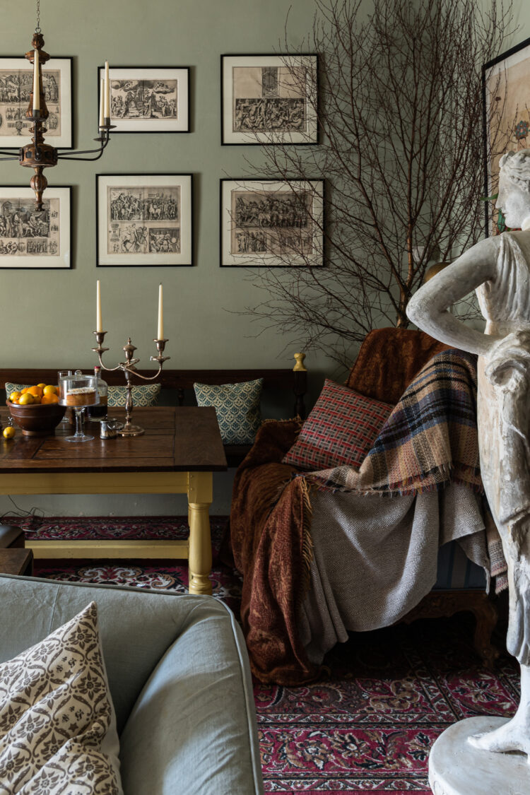 Green wall of framed prints with couch