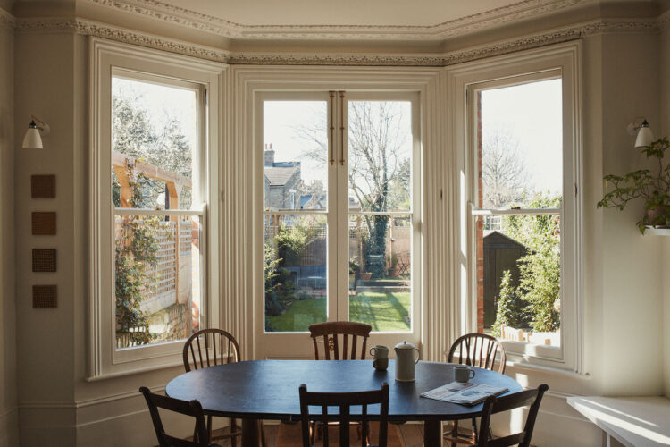 Dining table sitting in front of large bay windows