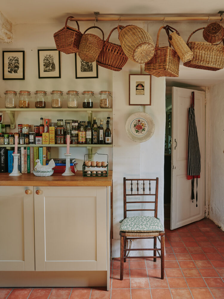 Kitchen with wooden bench, wall shelving and baskets hung from ceiling