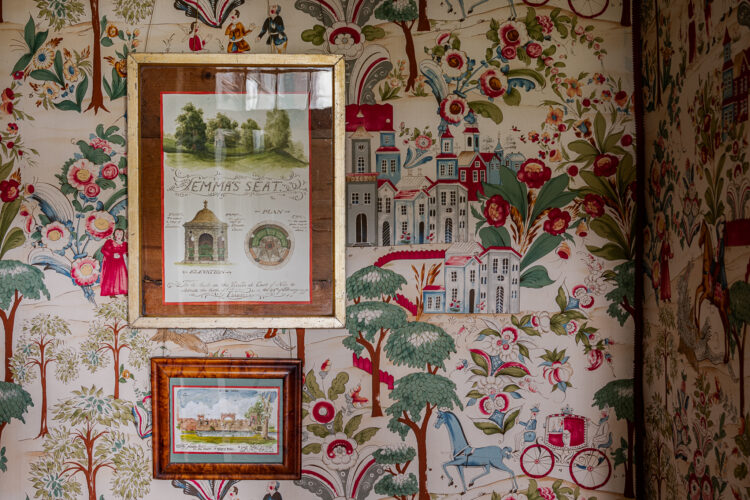 Wallpapered wall with two framed drawinds